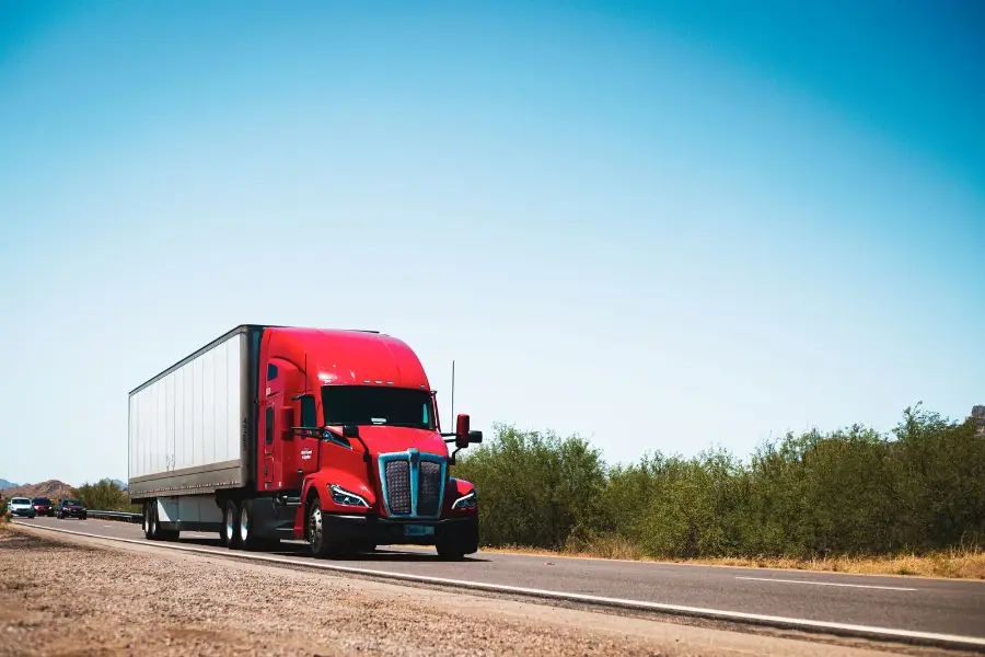 Red semi truck pulling a white dry van trailer on a US highway